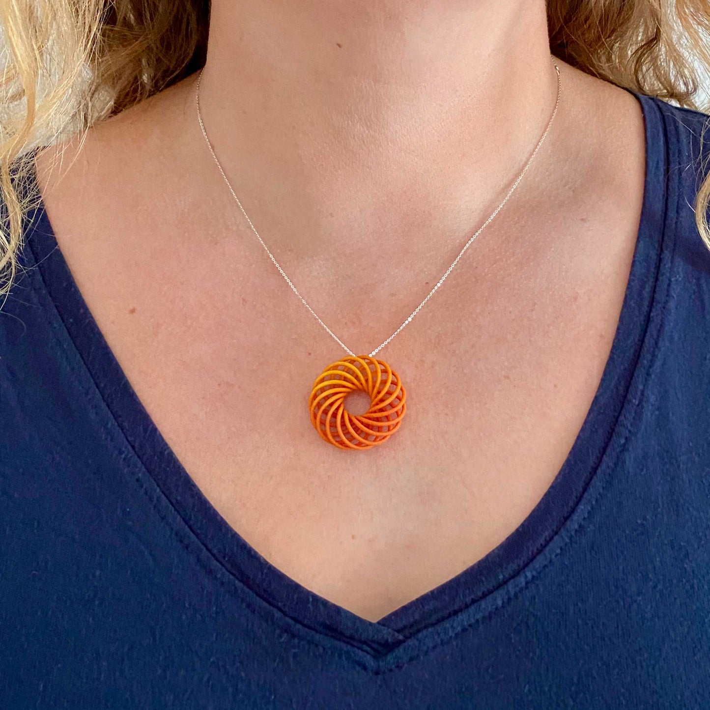 Katy wearing small Vortex 3D printed pendant in teal on a silver chain