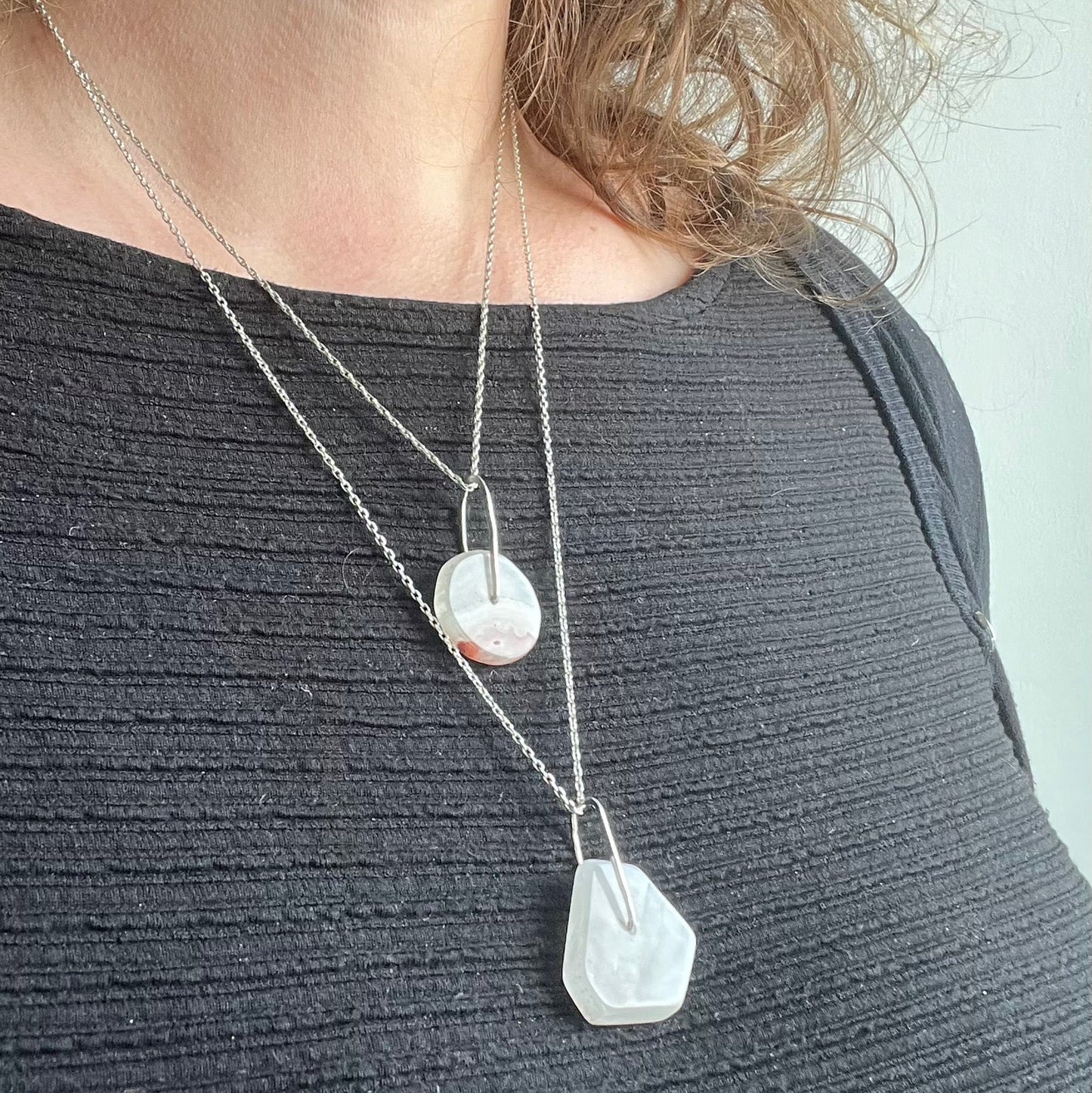 model wearing two stone pendants