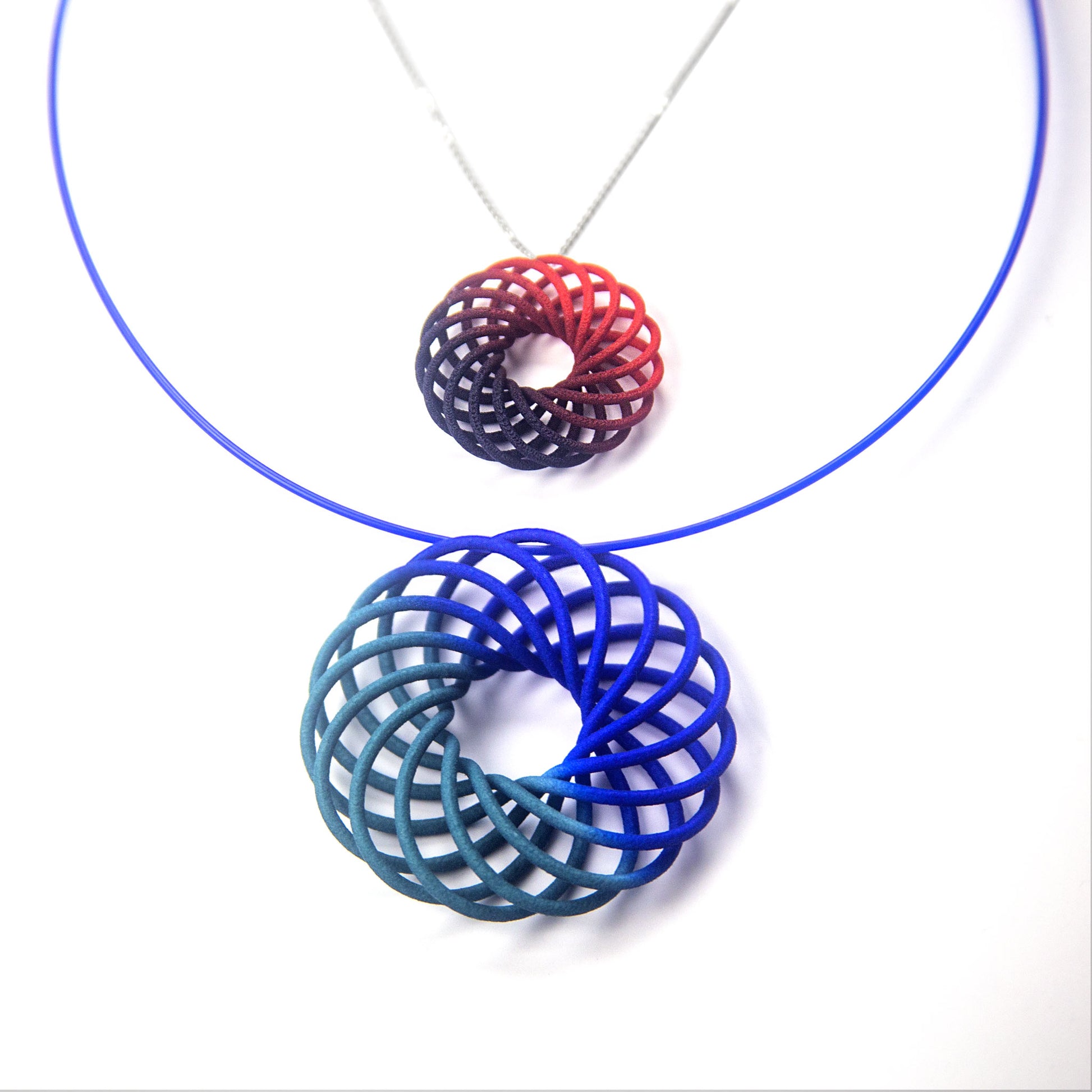 Small Vortex scarlet to purple fade pendant on a silver chain next to 5cm vortex pendant in teal to blue fade
